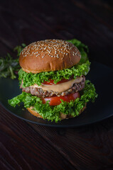 Appetizing fatty burger with pork cutlet and cheese sauce and salad. Harmful but delicious fast food.