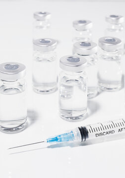 COVID-19 vaccine vials and syringe on white background
