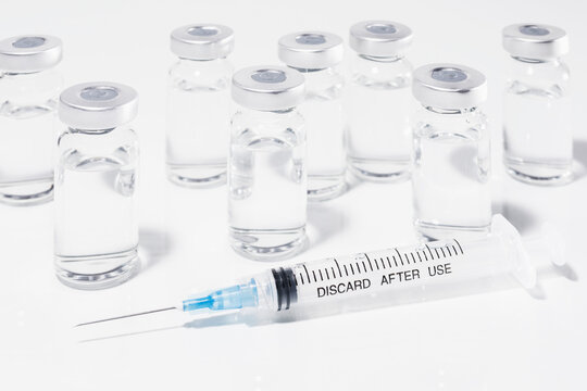 COVID-19 vaccine vials and syringe on white background
