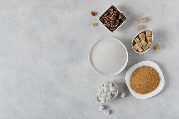 Different white and brown sugar in assortment top view on grey background.