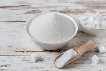 White sugar crystals and cubes of refined sugar.
