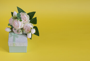 Gift box and bouquet of flowers on yellow background. The concept of congratulations for Valentine's Day, birthday, International Women's day and other holidays. Copy space