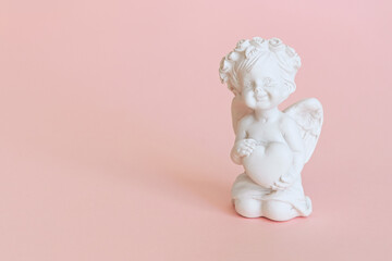 figurine of an angel Cupid with a bow on a pink background. Valentine's Day.