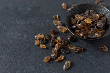 Brown caramelized pieces of cane sugar on black background.
