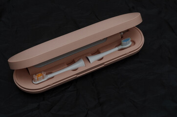 pink plastic case with electric toothbrush and attachments on black background