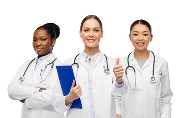 Fototapeta premium medicine, profession and healthcare concept - international group of happy smiling female doctors in white coat showing clipboard and thumbs up gesture