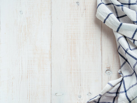 View From Above On White Wooden Table With Linen Kitchen Towel Or Textile Napkin. Blue Tablecloth On White Wood Tabletop. Copy Space For Text. Can Use As Mock Up For Design.