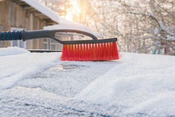 Brush for cleaning snow from a car close-up. A brush with red bristles against the backdrop of...