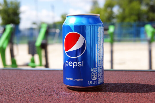 A metal bottle of Pepsi drink on the background of a street sports ground.
