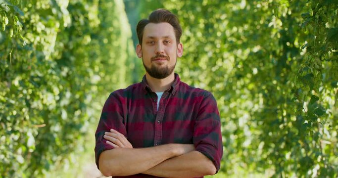 A portrait of a farmer folding his arms while standing in the hop field.