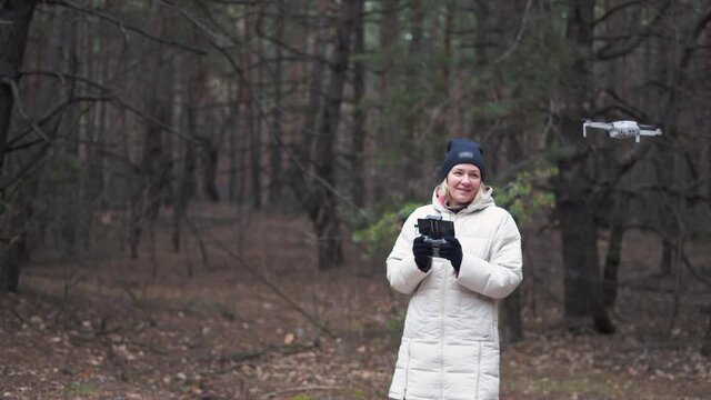 Caucasian Woman Flying Aerial Drone In Autumn Forest. Tech Savvy Middle Age Woman. Hobby Modern