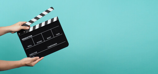 Hand is holding Black clapper board or clapperboard or movie slate on mint green or Turquoise background. - obrazy, fototapety, plakaty