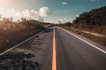 Fototapeta premium Empty asphalt road through the green field and clouds on blue sky.