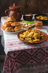 Ukrainian or Russian traditional feast. Traditional russian fried potatoes with bacon with garlic bread. Ukrainian ornament. Copy space.