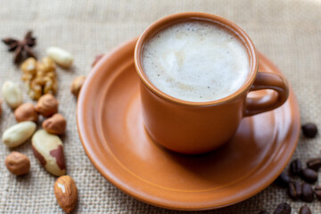 Black coffee on the table with burlap cotton, chocolate, cinnamon, nuts and roasted coffee beans