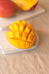 A ripe, juicy mango lies on the white background of the table and the snout, the whole fruit and cut into sections