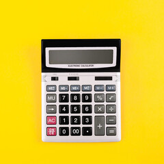 Large silver calculator with black buttons on yellow background with copy space. Conceptual photo of calculation, counting, accounting, computing, profit, loss, tax. Business card. Digital stationery