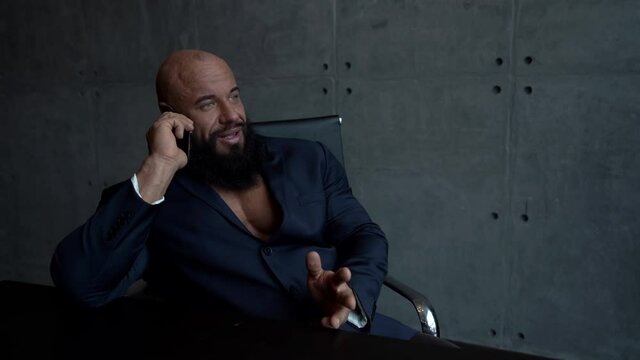 busy man is negotiating by cell phone sitting in his home office, sexy muscular guy, portrait indoors