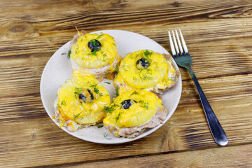 Pieces of baked pork with pineapple, cheese and olive on a wooden table