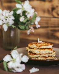 Delicious apple pancakes and apple flowers on a wooden background. Vertical