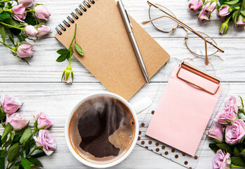 Workspace with diary, notebook, clipboard, roses on white background.