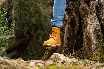 close-up winter boots for man in a forest ,man sitting on olive tree , mediterranean landscape , cool leather boots