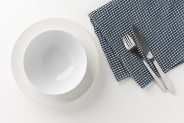 White empty plates set on the table with knives and forks and tablecloths. Ready to eat