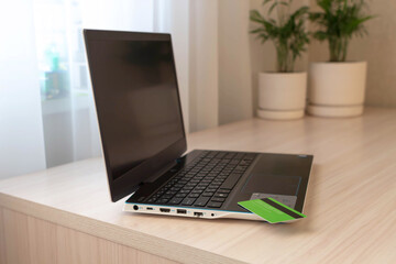 Shopping online concept . Laptop bank card on table at home on background of houseplants.