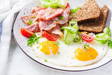 English breakfast - fried egg, bacon, tomatoes  and bread.