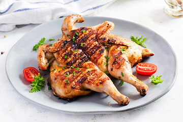 Grilled chicken Tabaka on blue plate. Georgian cuisine.