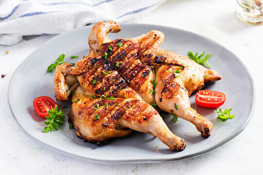 Grilled chicken Tabaka on blue plate. Georgian cuisine.