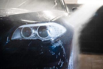 Auto at the car wash. Flushing foam from car with pressure washer