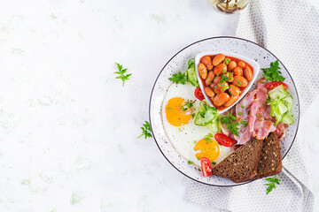 English breakfast - fried egg, beans, bacon, tomatoes  and bread. Top view, flat lay, overhead