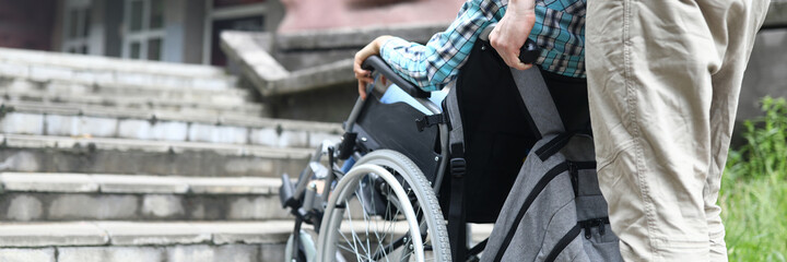 Close-up of male helping woman to get upstairs outdoors. Man taking care of female friend. Walking in city centre. Fresh air and joyful life. Disabled people concept