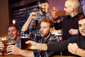 Soccer fans celebrating victory. Group of people together indoors in the pub have fun at weekend time
