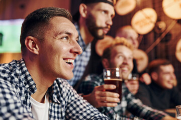 Soccer fans celebrating victory. Group of people together indoors in the pub have fun at weekend time
