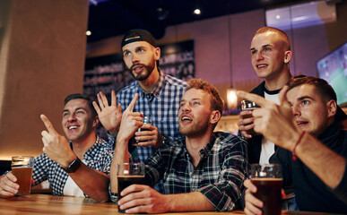 Football fans watching TV. Group of people together indoors in the pub have fun at weekend time