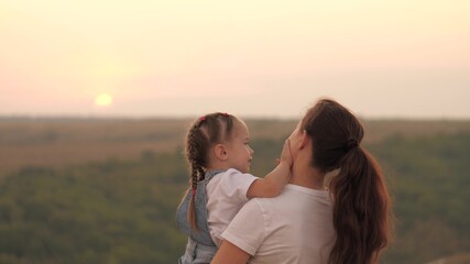 Kid and mama are having fun in the park. Mom plays with little girl in her hands. Mother and beloved child have fun together. Happy family. Walking outdoors with your baby