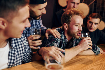 Sad man feels bad. Group of people together indoors in the pub have fun at weekend time