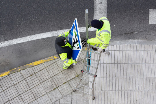 Workers installing a new road sign on street sidewalk