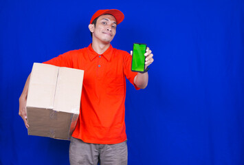 Delivery Man Showing Phone Holding Box. Phone Green Screen. Delivery Boy Smiling. Man with Parcel in Hands isolated blue background
