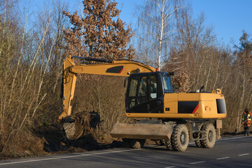A bucket excavator clears the roadside. Road works. Laying a new road. Loading excavator clay and stones