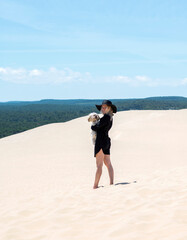 girl on a sand dune in a black hat and a beautiful forest view