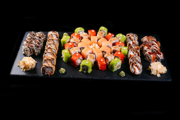 Sushi set. Maki and rolls with tuna, salmon, shrimp, crab, red caviar and avocado. served with wasabi and ginger on black background. Top view of assorted sushi. Japanese  food. professional photo