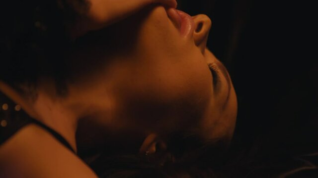 young woman in sexy bra touching neck on dark background