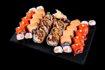 Sushi set. Maki and rolls with tuna, salmon, shrimp, crab, red caviar and avocado. served with wasabi and ginger on black background. Top view of assorted sushi. Japanese  food. professional photo
