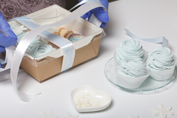 Woman in rubber gloves makes marshmallows. Packs in a gift box and ties with a ribbon. Close-up shot.