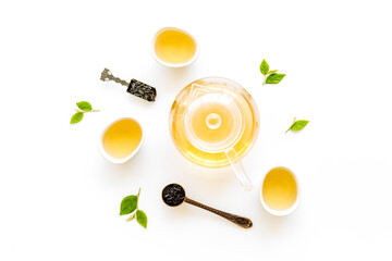 Tea green leaves with teapot and cups, top view. Tea ceremony concept.