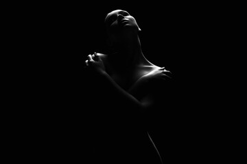Nude Woman silhouette under light in the dark