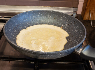 Preparing the dough and frying crepes in the home kitchen, natural light.